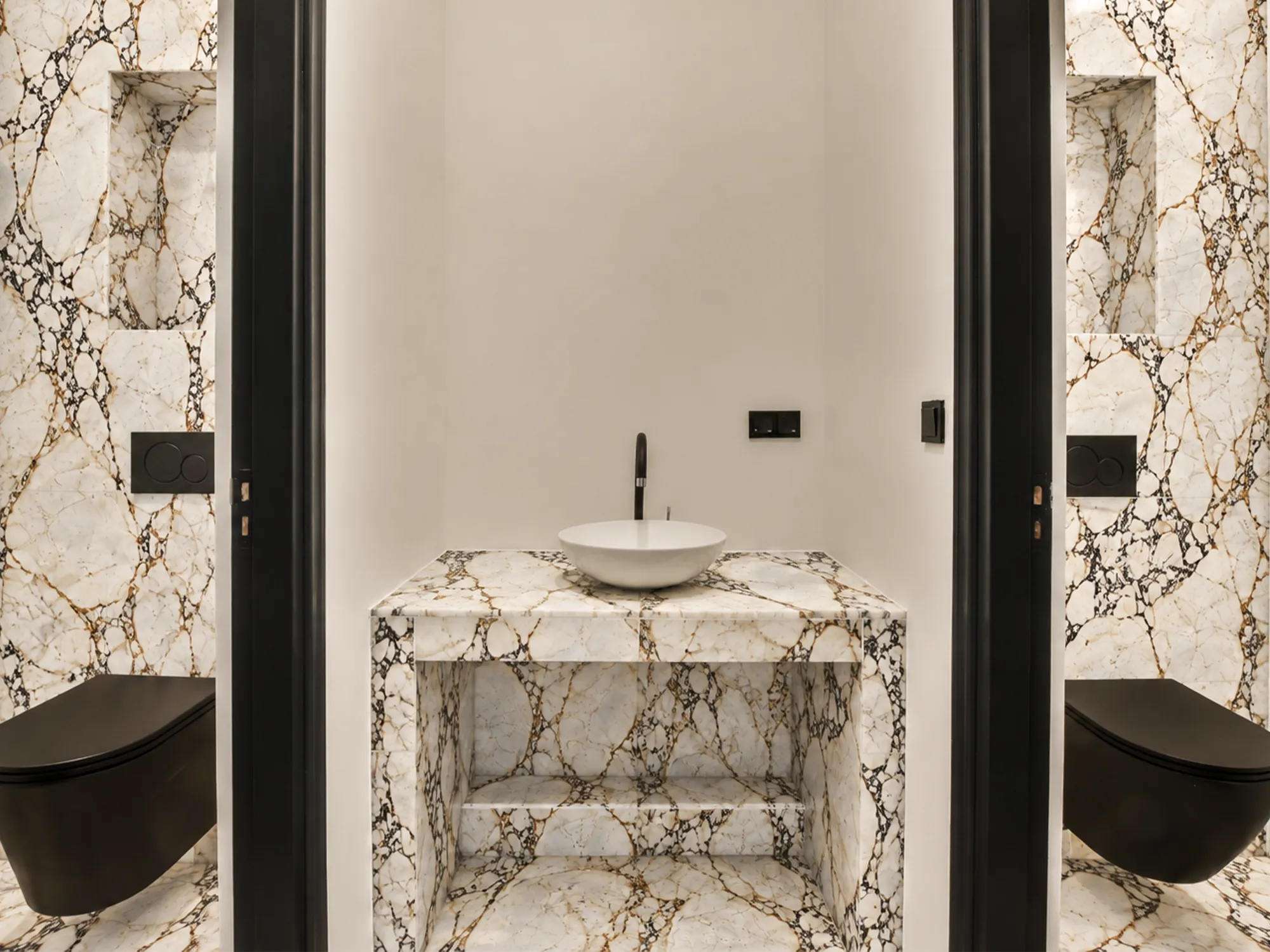 Calacatta Viola marble vanity, wall panels, and flooring with dark and gold-brown veining in a bathroom with black fixtures.