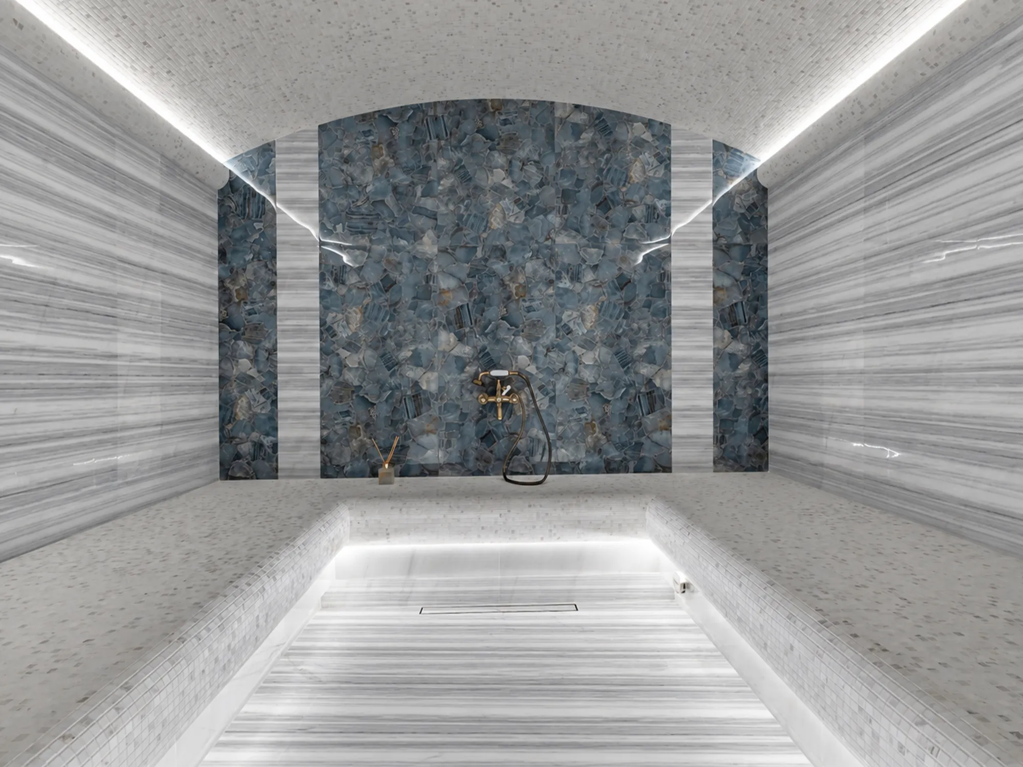 Marmara Equator marble walls and floor with parallel gray and white stripes, alongside mosaic benches and blue wall panels.