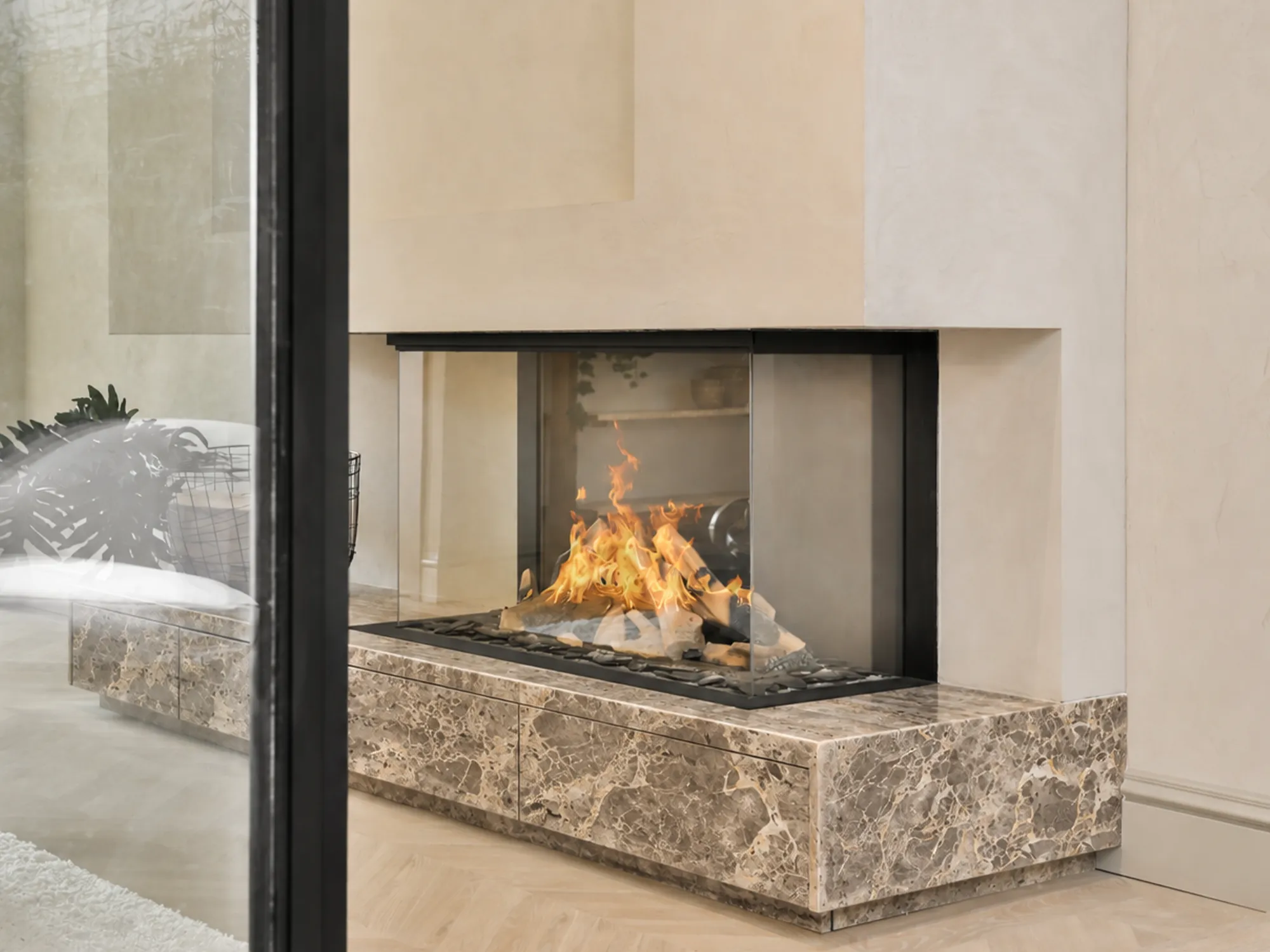 Breccia Grey marble hearth and base panels with warm gray tones and cream veining beneath a glass-enclosed fireplace.