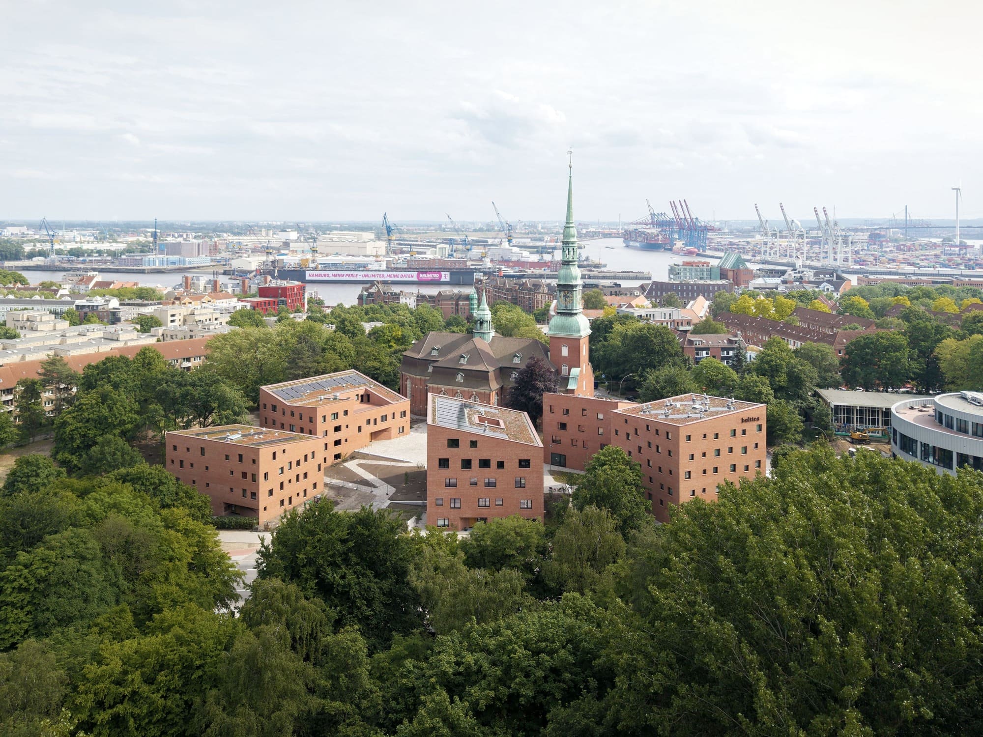 Luftaufnahme des Trinitatis Quartiers in Hamburg-Altona mit Backsteinbauten, Kirchturm und dem Hafen im Hintergrund