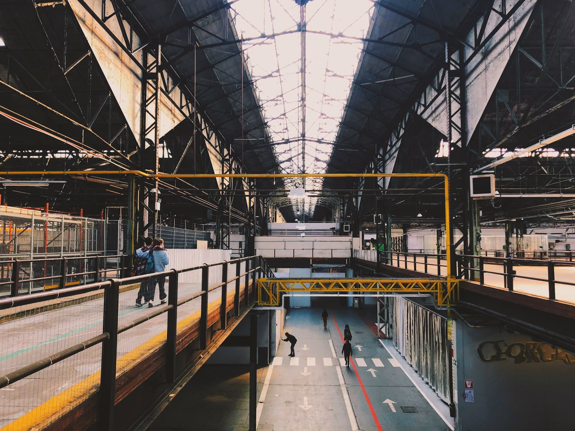 Large industrial hall with steel roof trusses and an overhead walkway