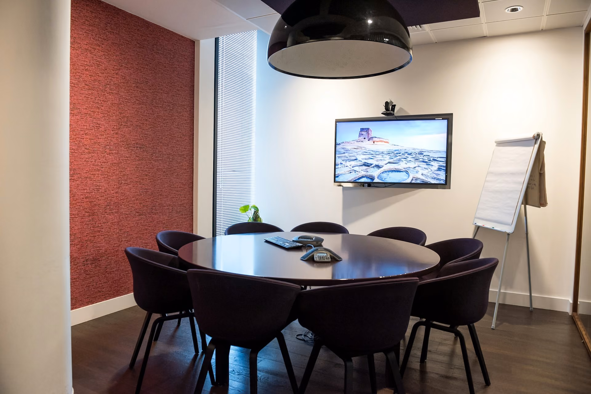 Small meeting room with a round table and video conferencing screen