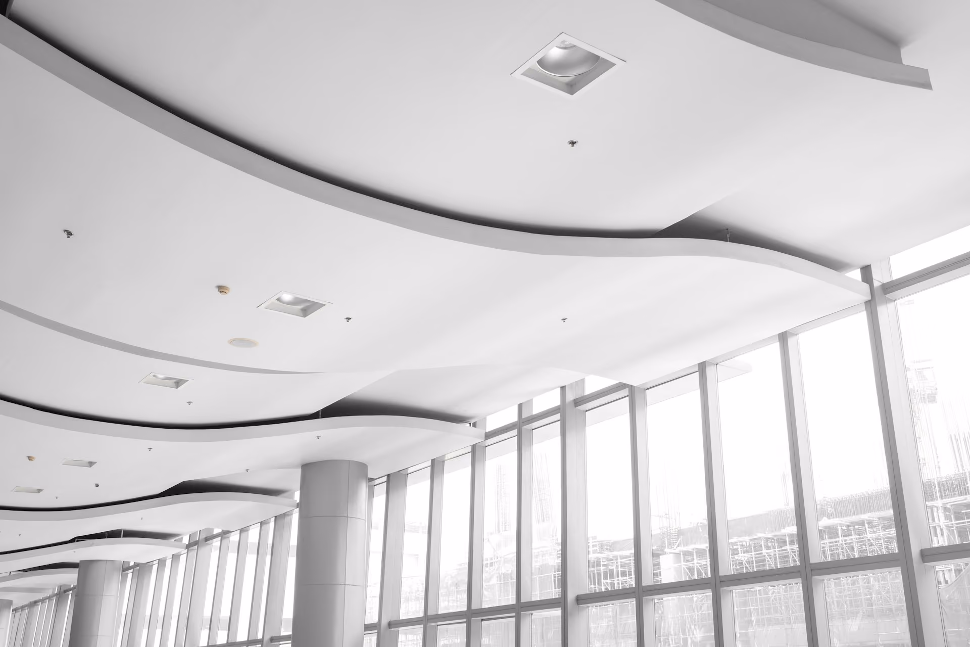 White curved suspended acoustic ceiling beside floor-to-ceiling glass windows