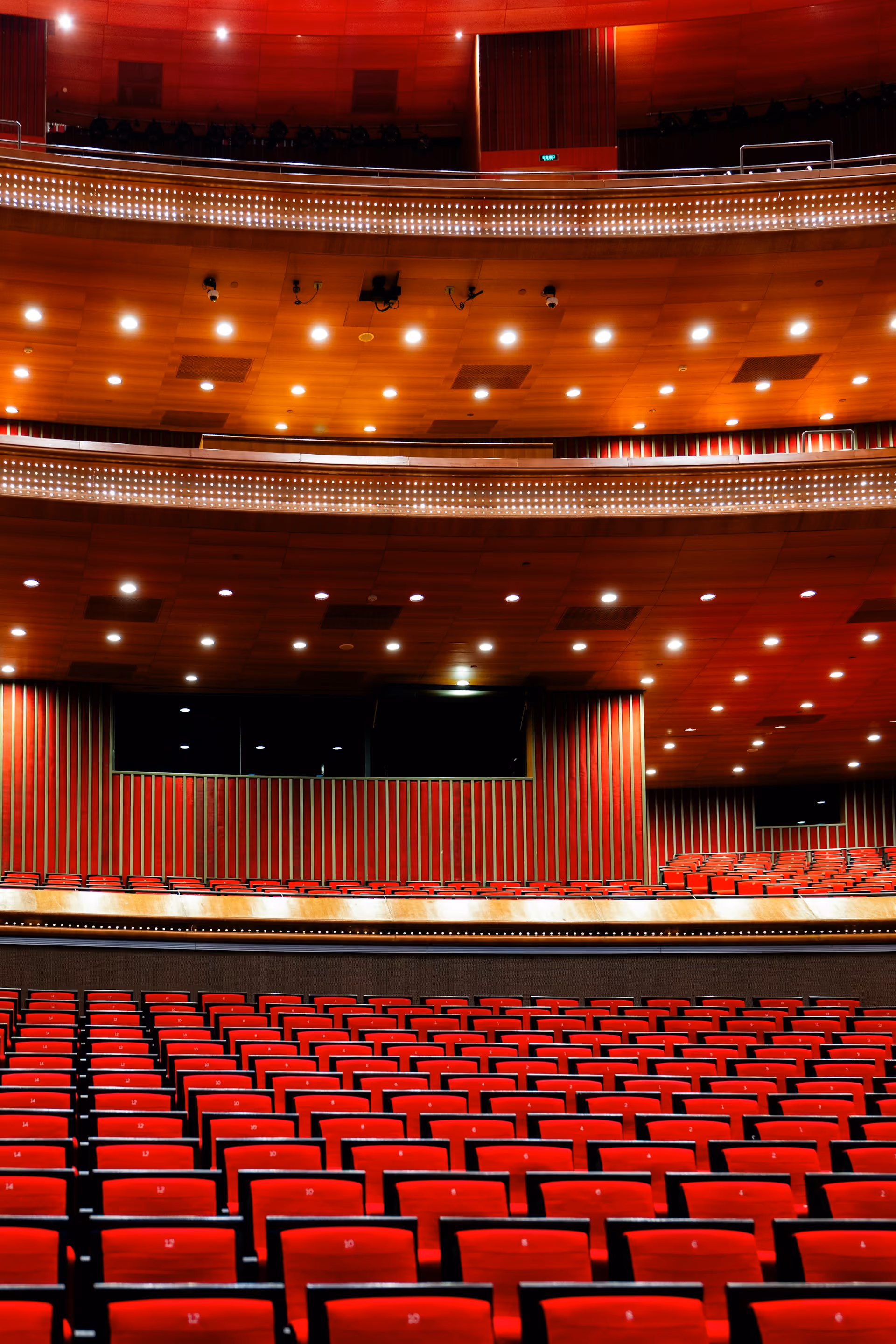 Auditorium with red seating, timber wall panelling and a stage