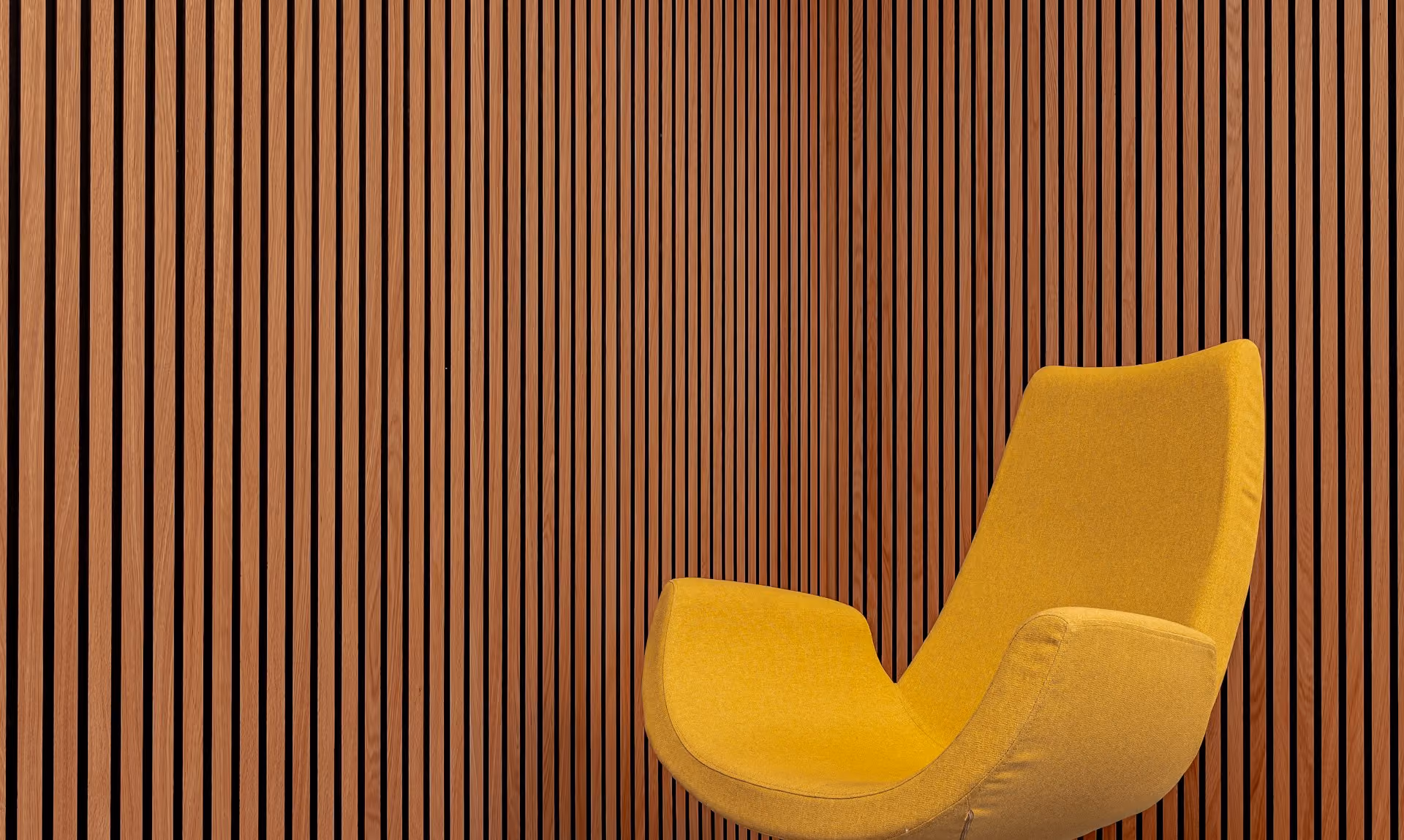 Vertical timber slat acoustic wall with a yellow armchair