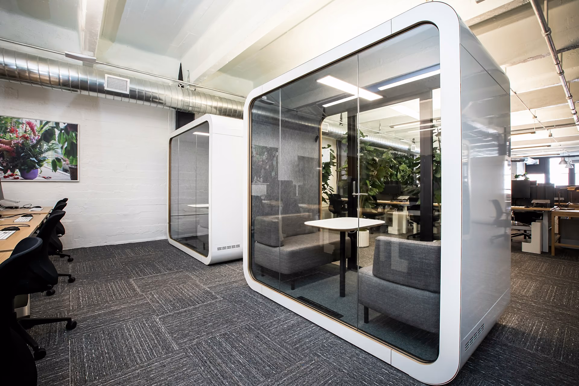 Glass acoustic pod with meeting seats in an open-plan office