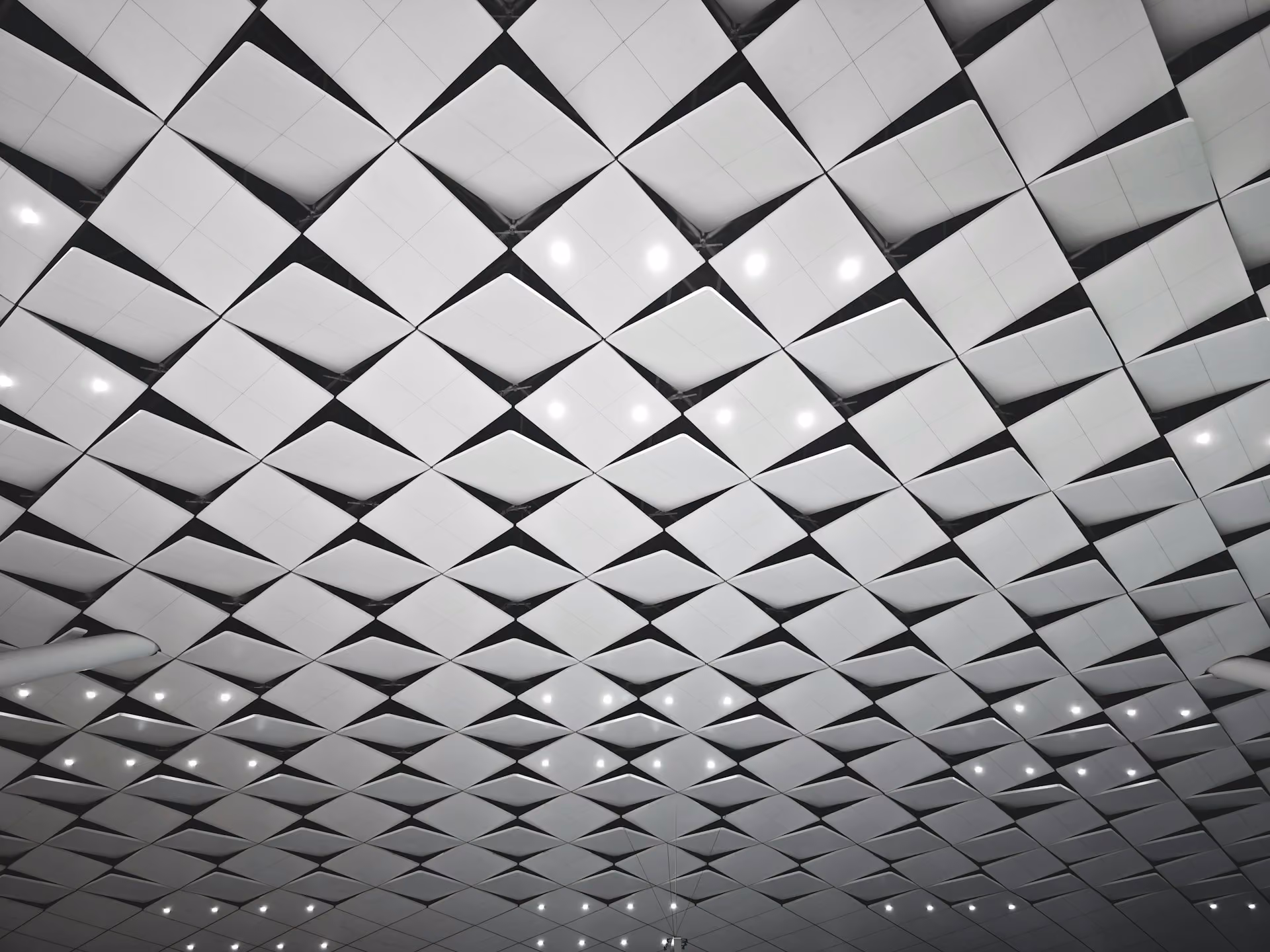 Faceted white acoustic ceiling panels with recessed downlights