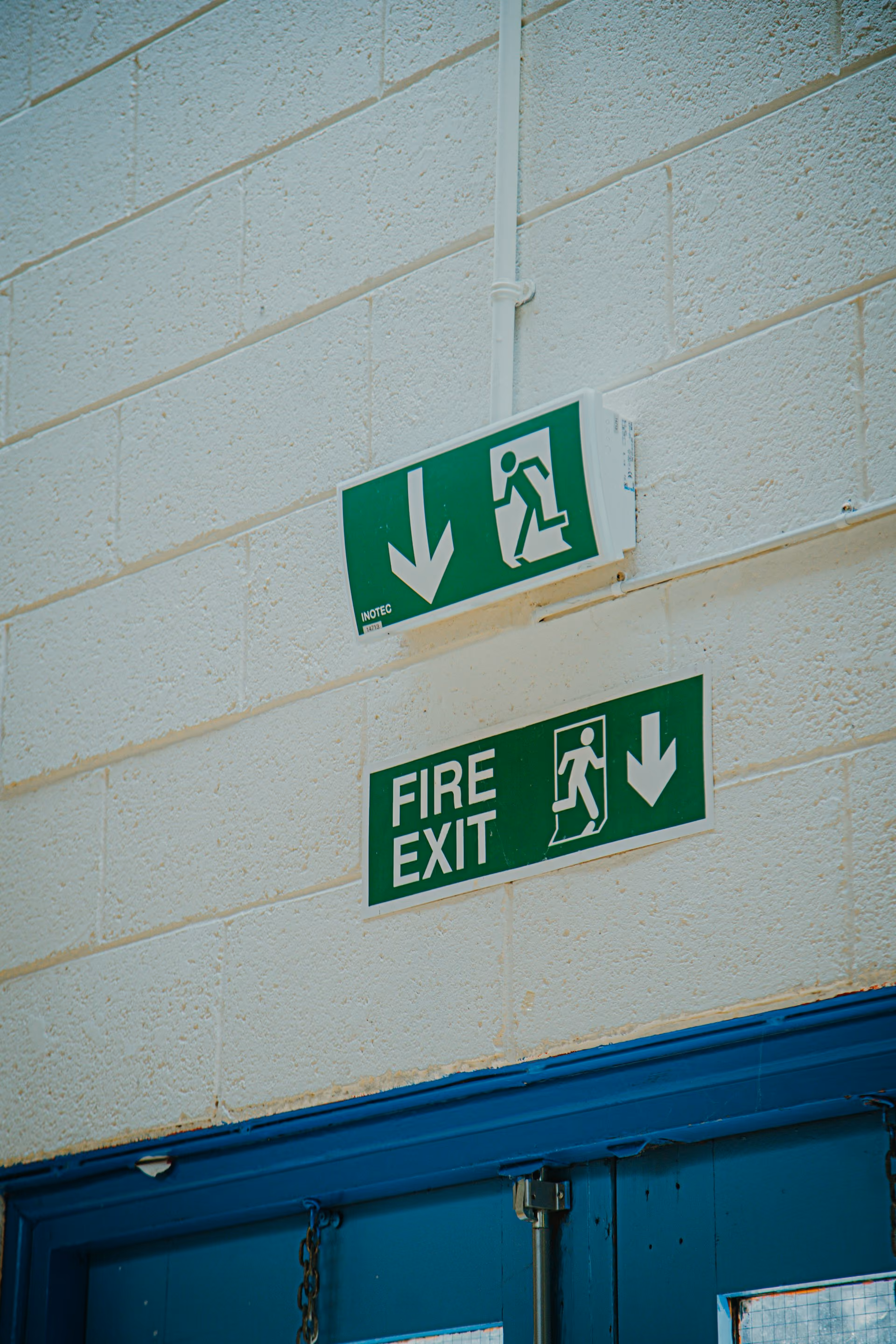 Green fire exit signs on a painted block wall