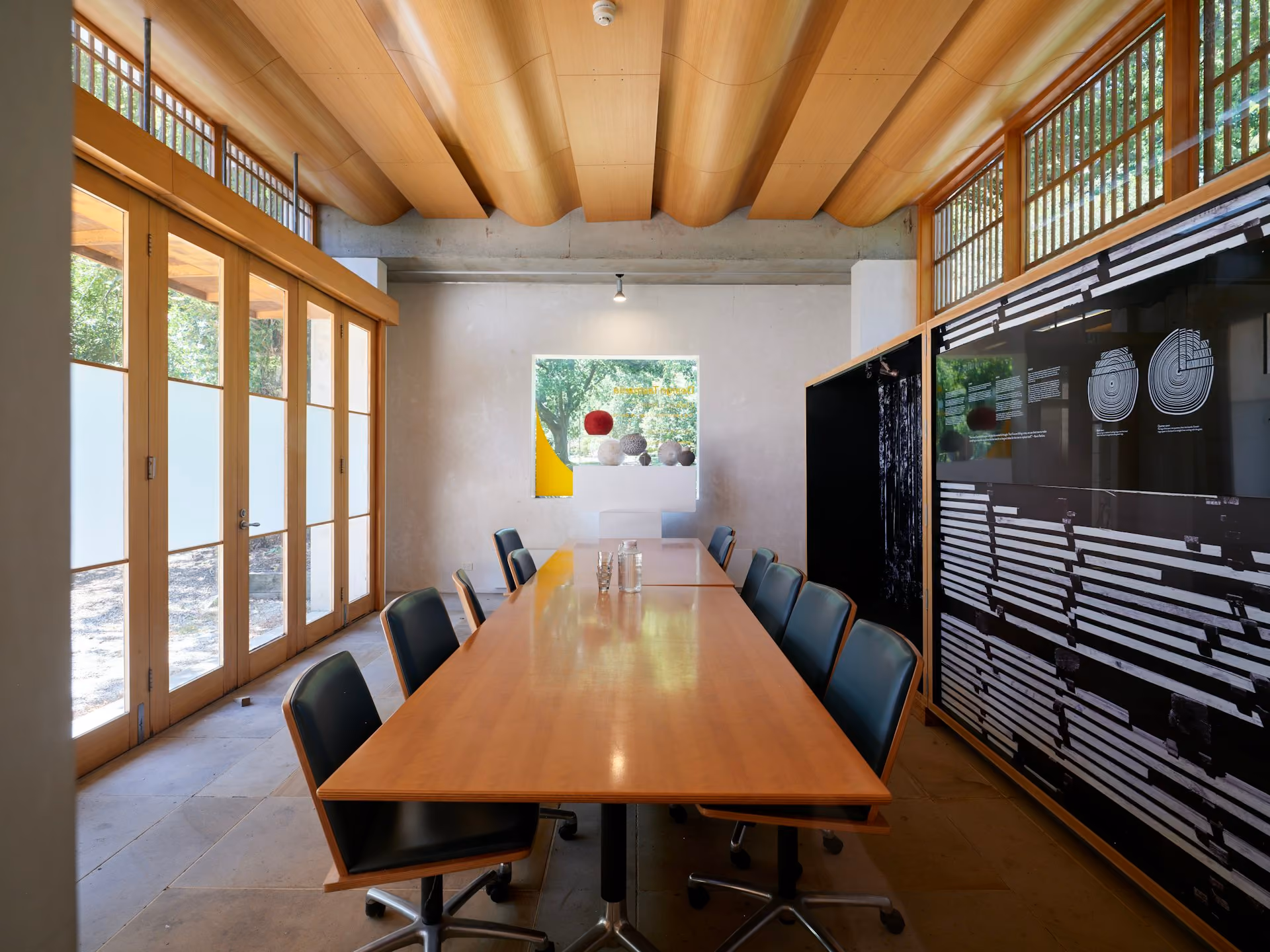 Modern glass meeting room with a long wooden table and chairs
