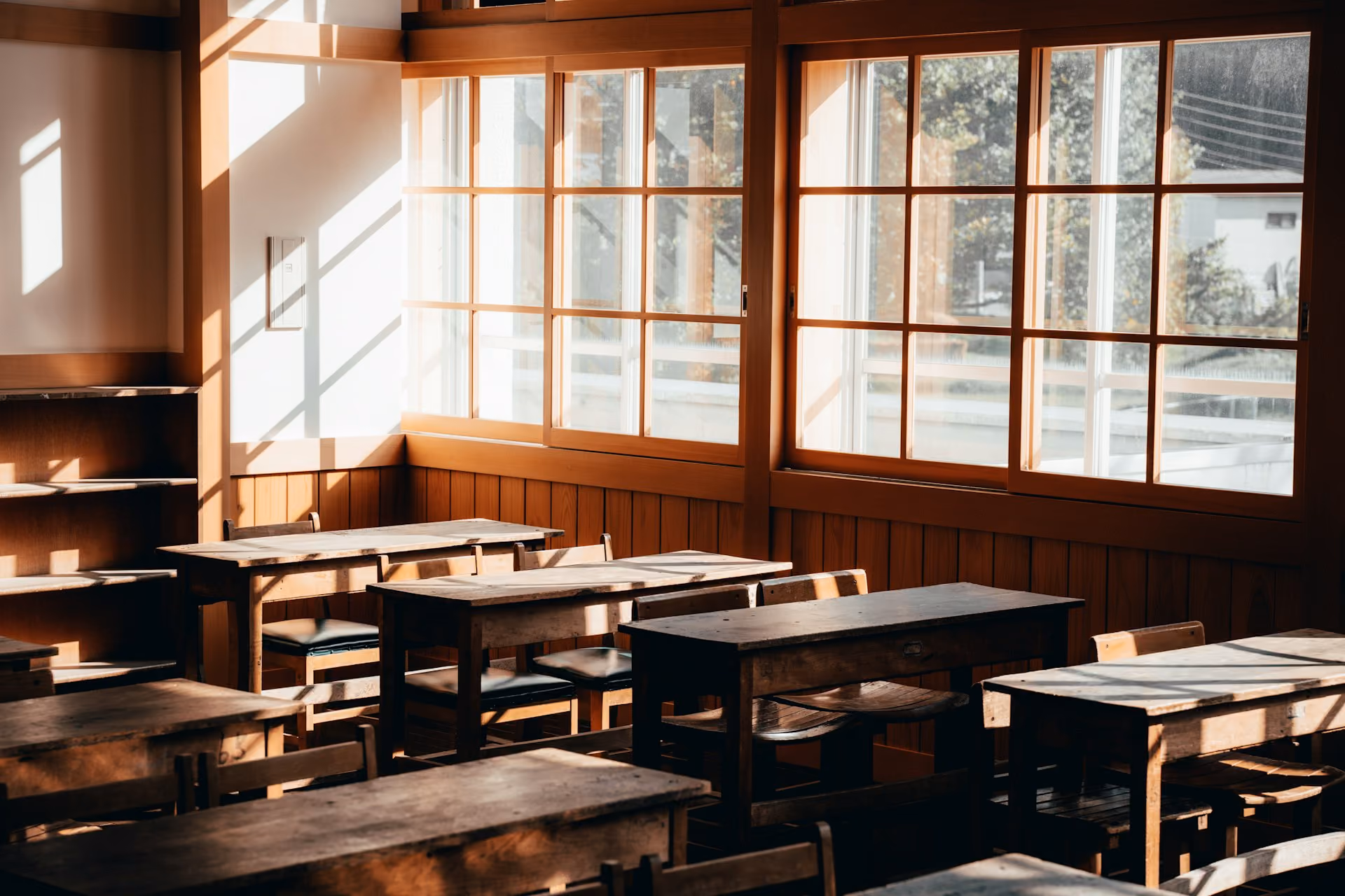 Sunlit classroom with timber desks and large windows before acoustic treatment