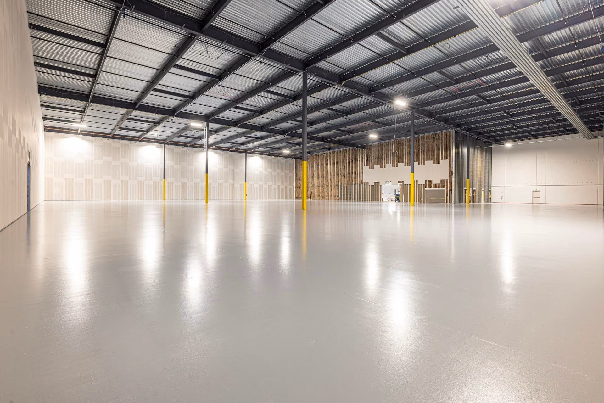 Empty industrial warehouse with polished concrete floor and high metal roof