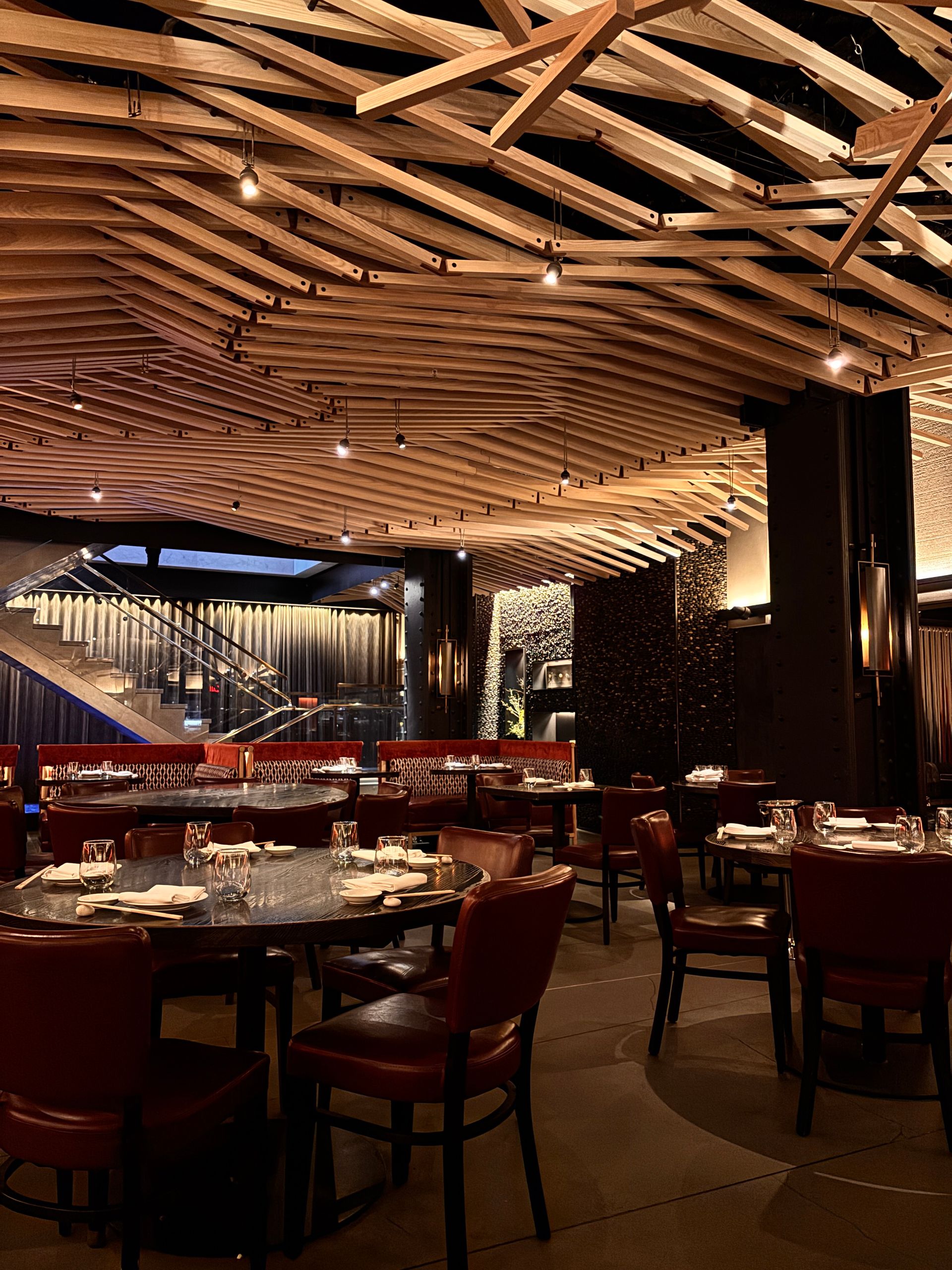 Restaurant dining room beneath a sculpted timber slat acoustic ceiling