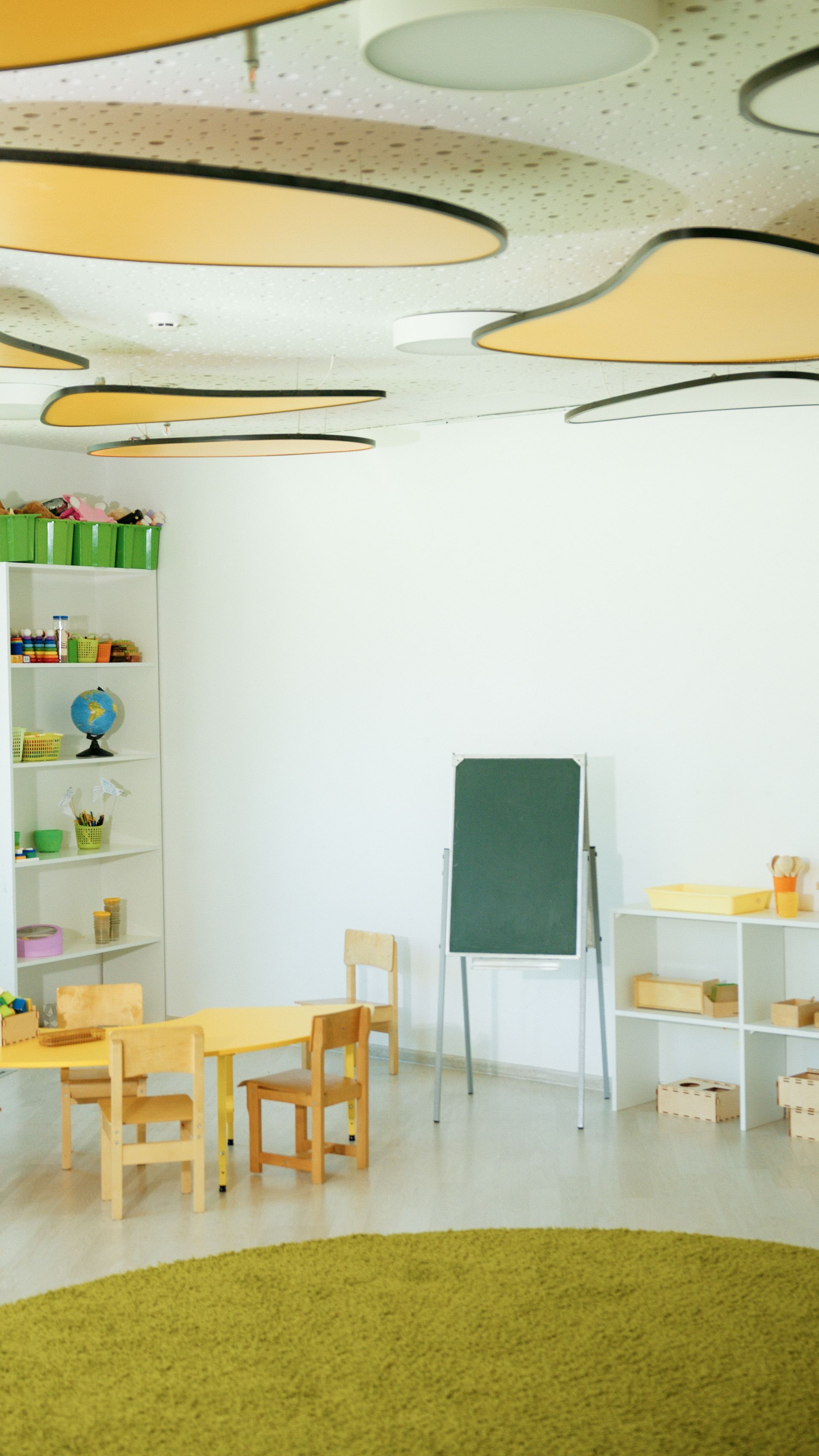 Nursery classroom with cloud-shaped acoustic ceiling islands above calm play areas