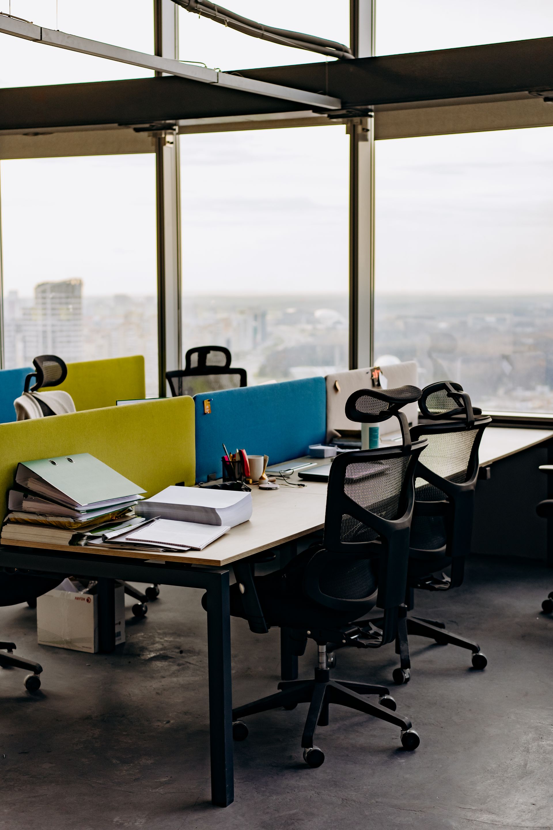 Open-plan office desks divided by coloured acoustic desk screens