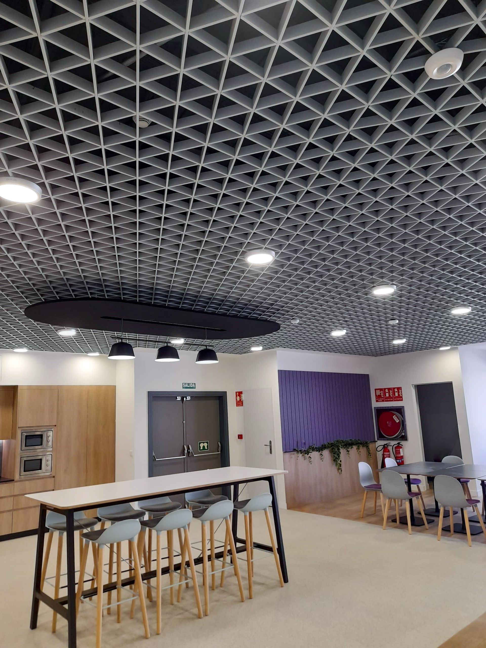 Office breakout area under an open-cell acoustic ceiling with a suspended raft