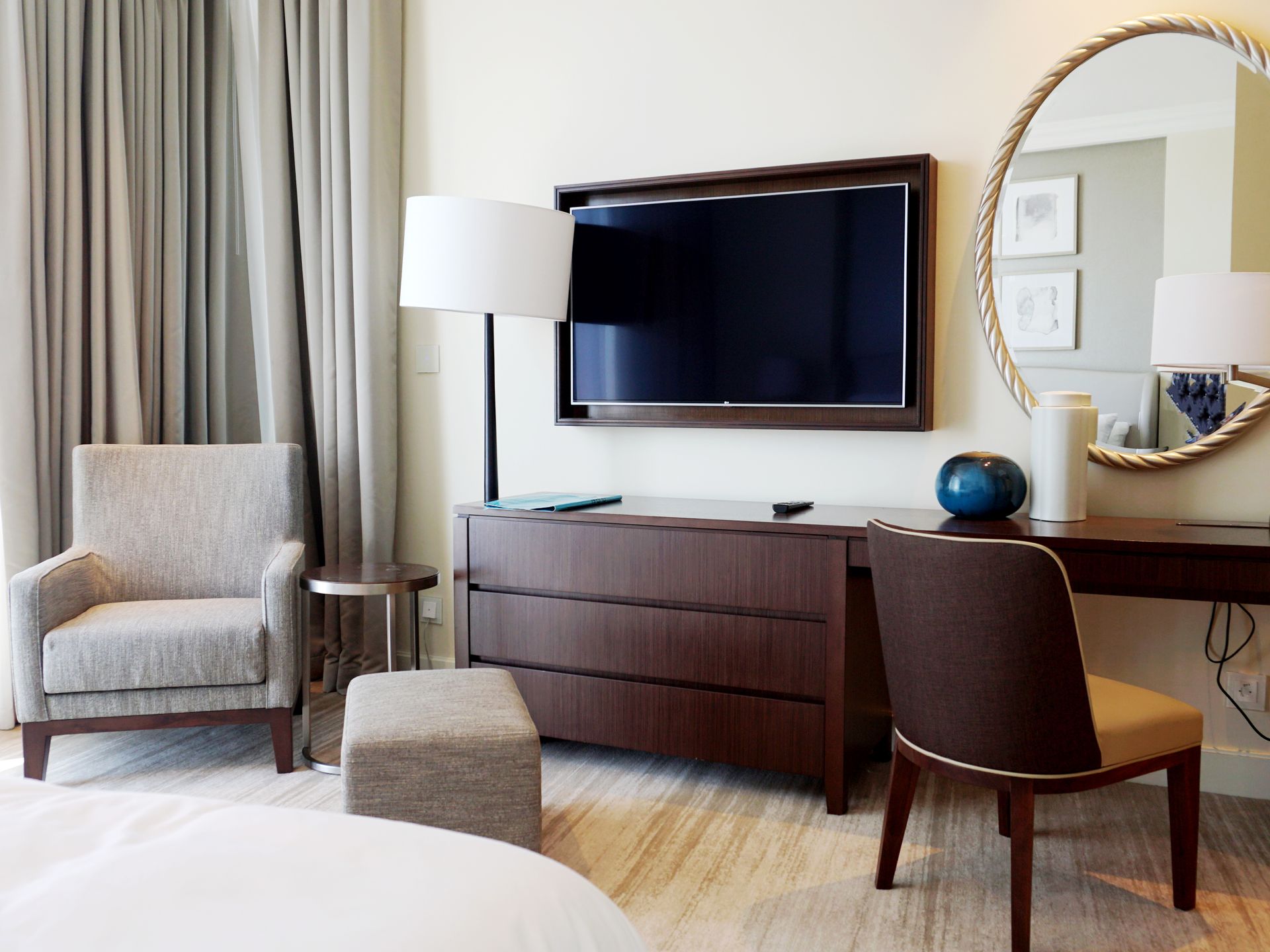 Hotel bedroom with desk and wall-mounted TV beside a shared wall