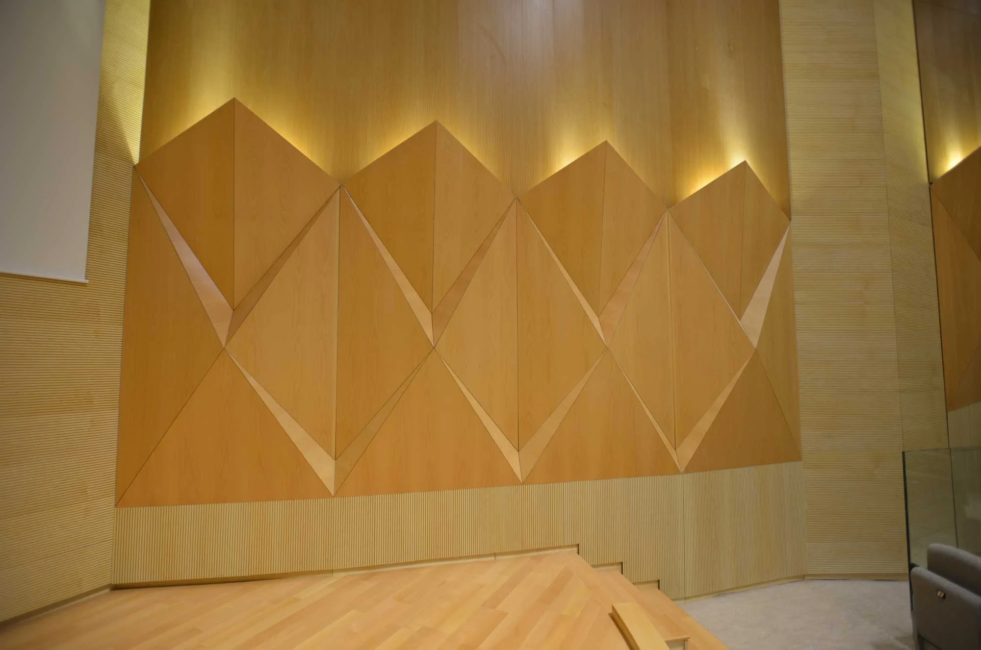 Faceted timber wall that scatters sound evenly across the room
