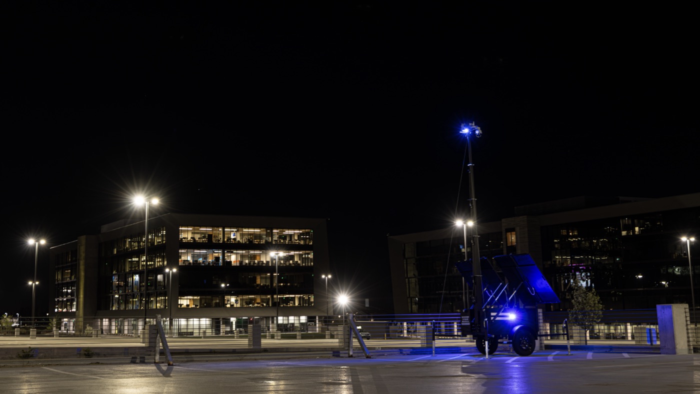 A unit parked outside a lit office building after dark, its blue strobe showing.