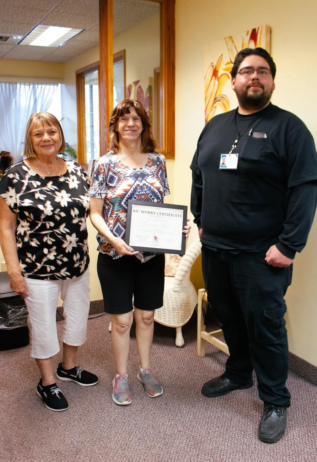 An AIC WORKS graduate holds her certificate, standing between two members of the AIC team