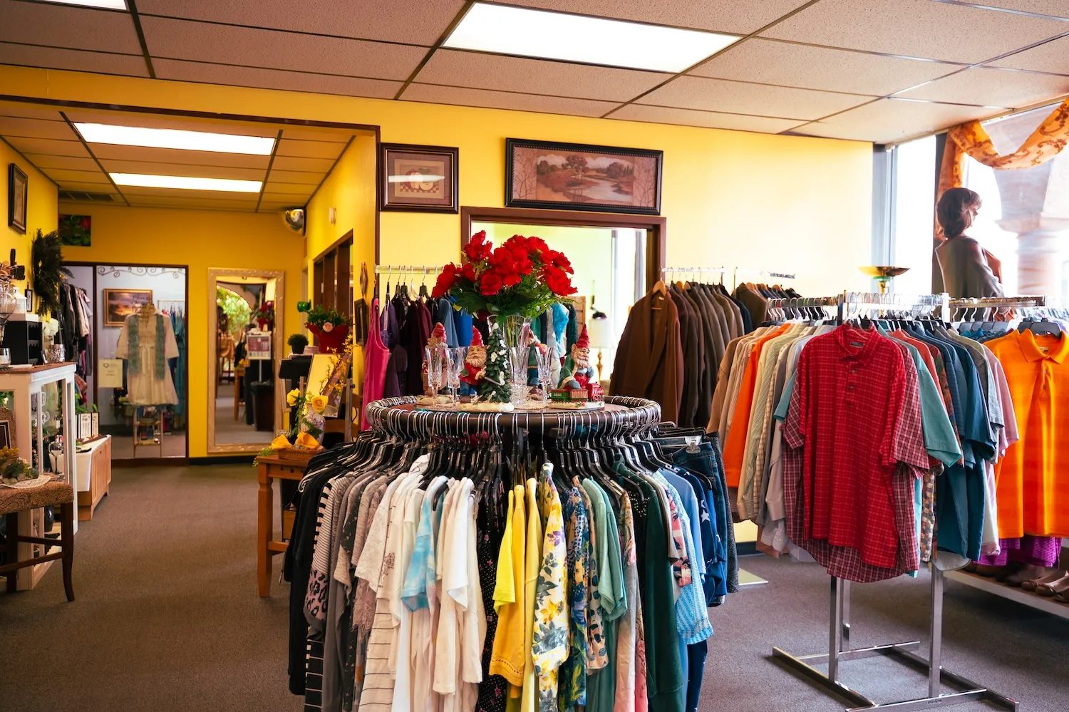 Clothing racks and a red floral display on the sales floor of Glorious Treasures Thrift Store, where AIC WORKS participants train with real customers
