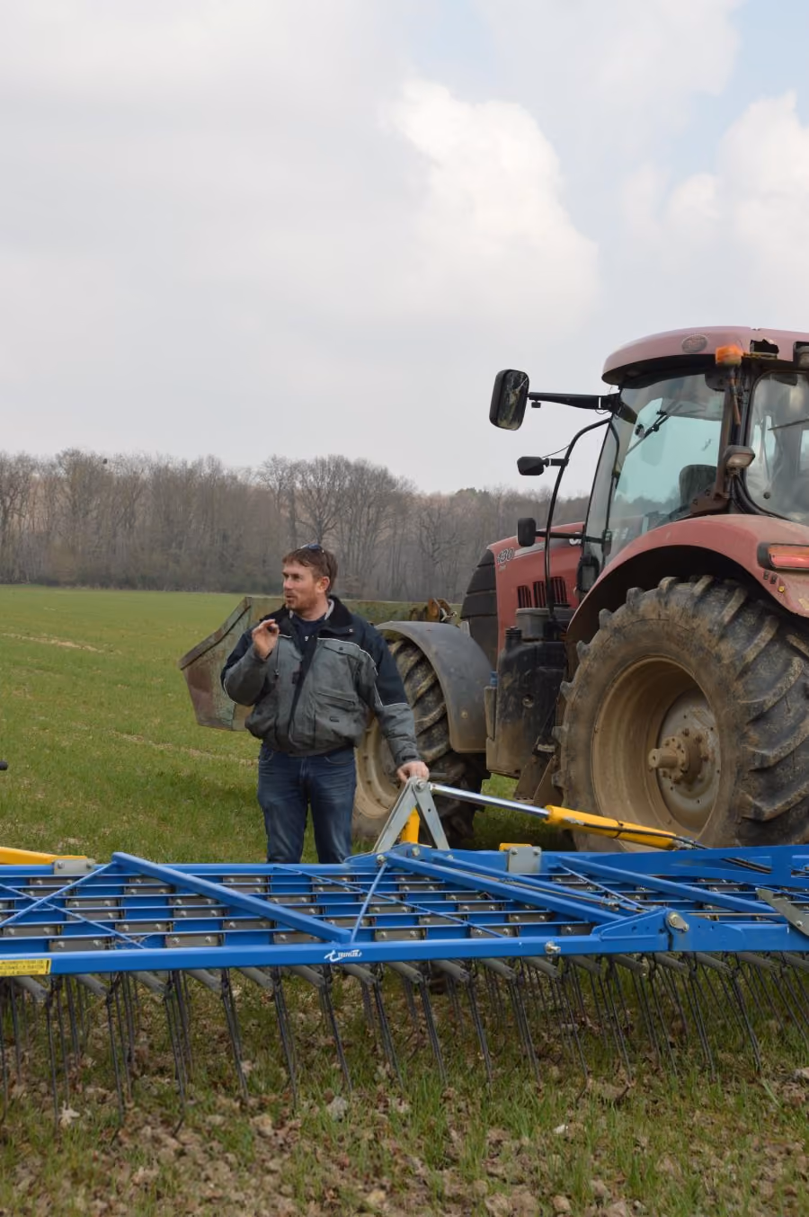 Sébastien devants la herse étrille lors de la visite de ferme - Mars 2025