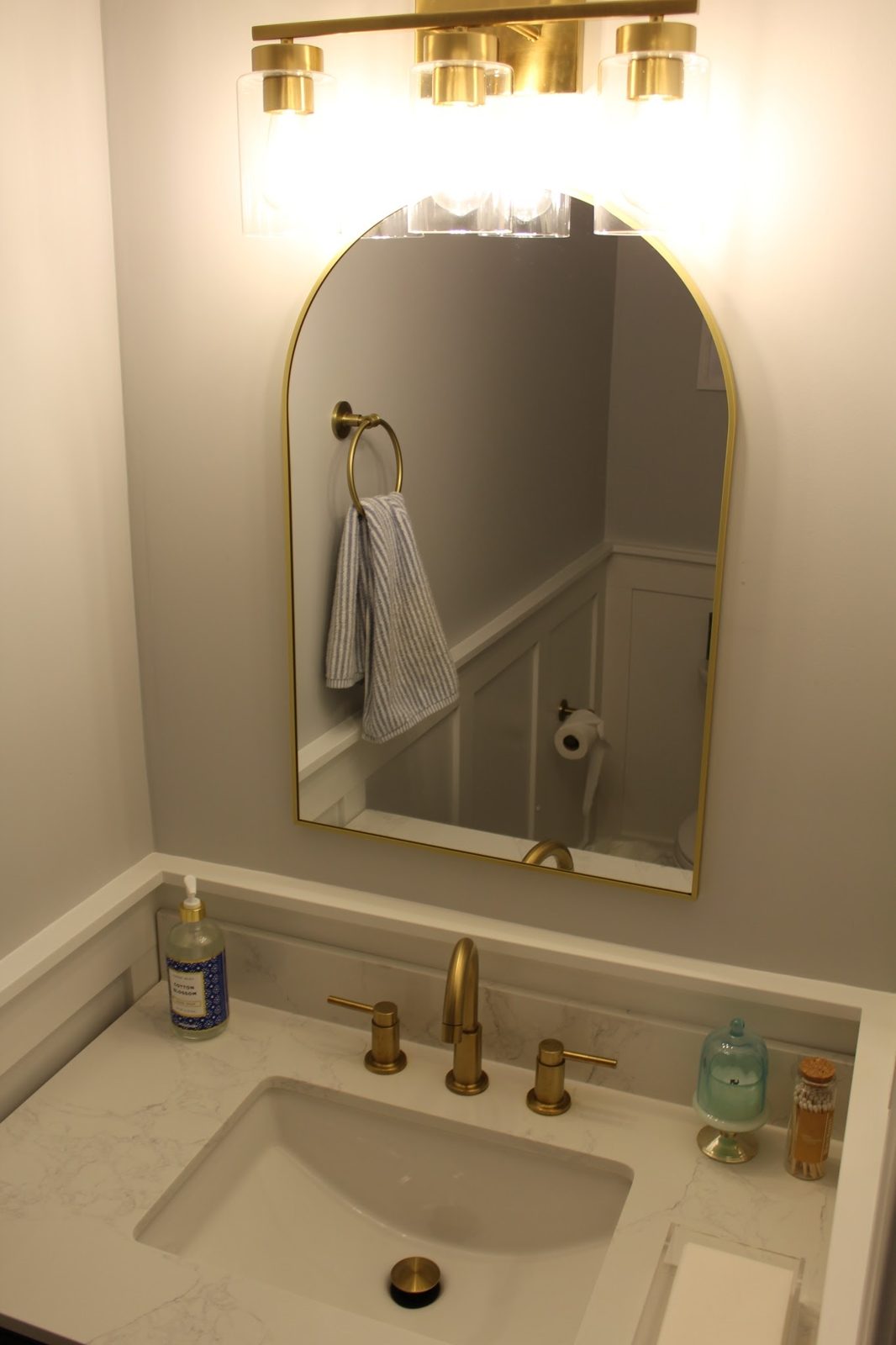 Powder room vanity, arched mirror, and light fixture