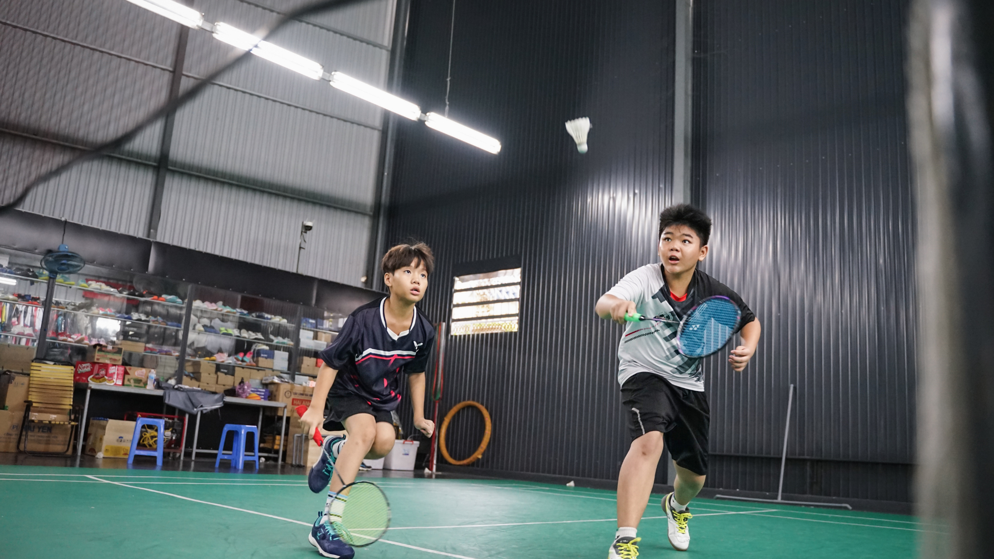 two badminton players going after the shuttle