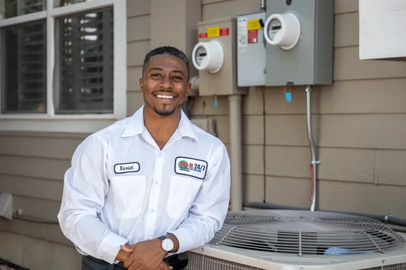 A technician leaning on an AC unit.