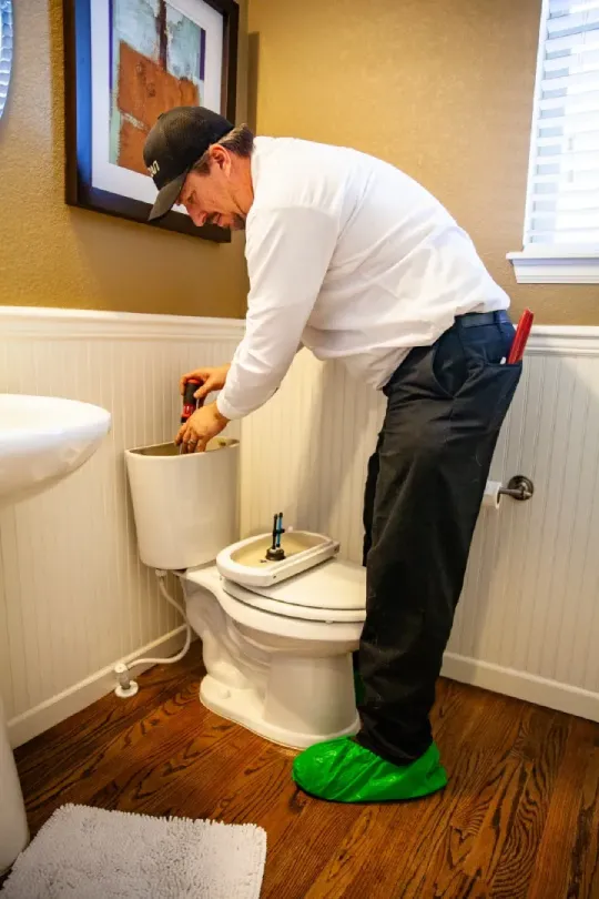 A technician working on a toilet in a customer's house.