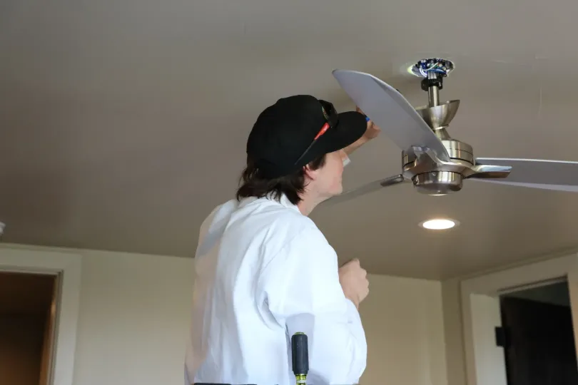 A technician looking at a ceiling fan.