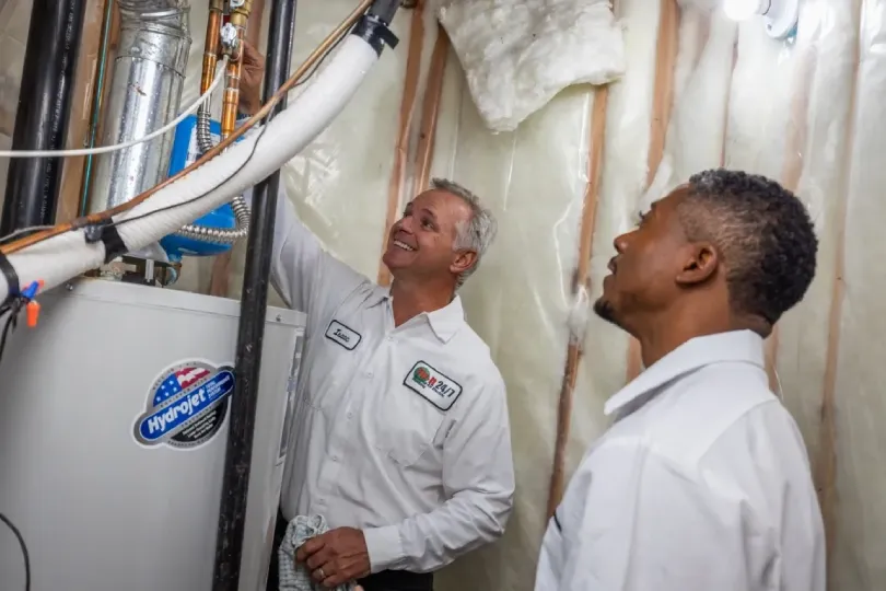 Two technicians working on a water heater.