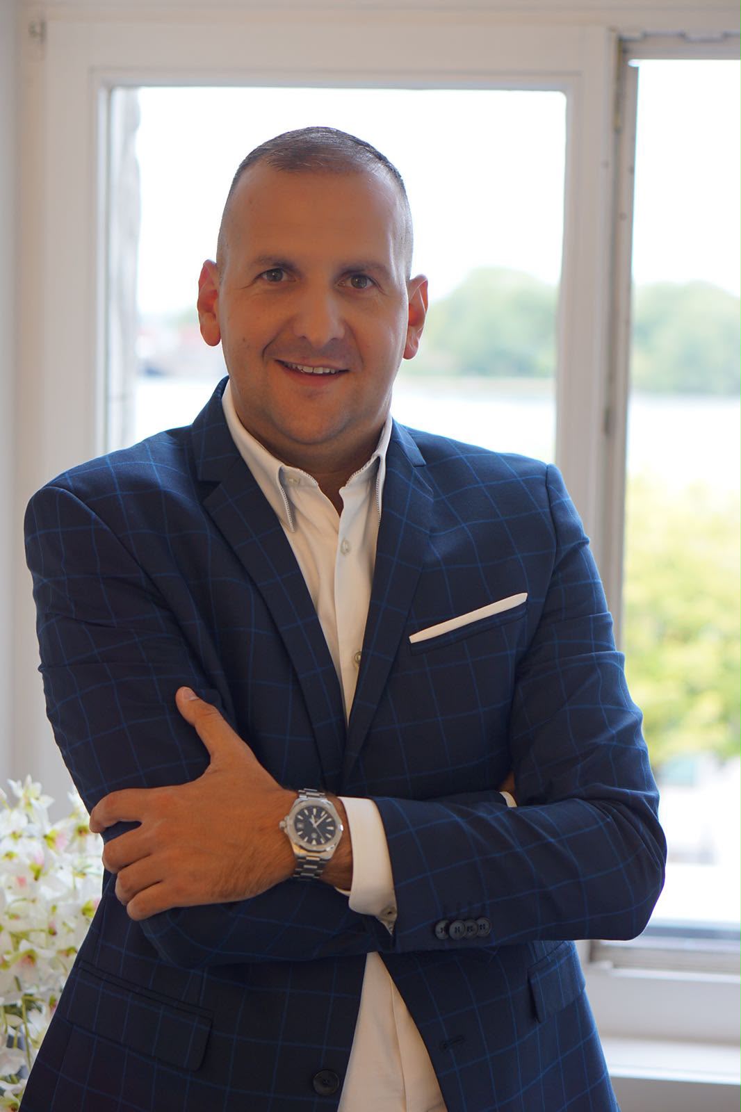 Portrait of Nikola Virijević in a navy blazer, arms crossed, at his Hamburg office
