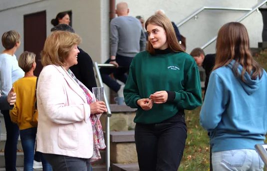 Eltern, Jugendliche und Mitarbeitende im Gespräch vor dem Gemeindehaus