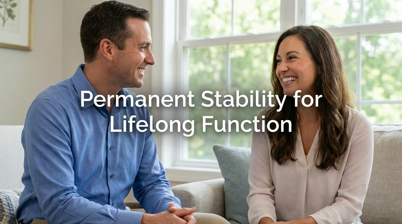 A man in a blue shirt and a woman in a white blouse sit on a couch near a window, smiling and talking, with text reading Permanent Stability for Lifelong Function.