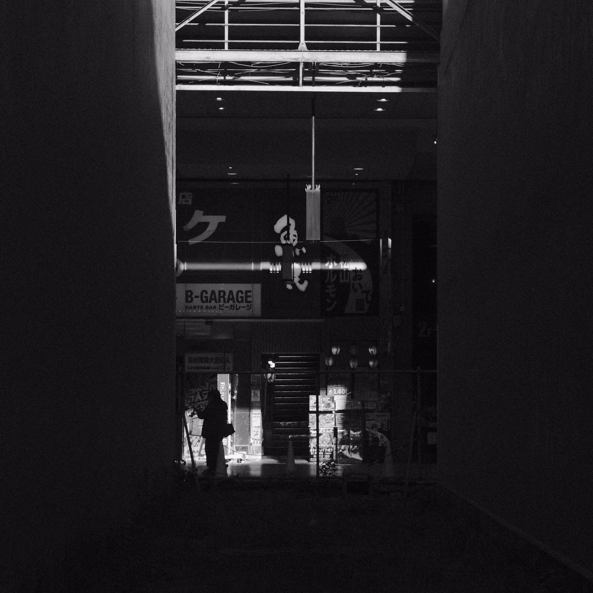 Fotografía urbana en blanco y negro con una silueta iluminada por un haz de luz entre un entorno oscuro saturado de letreros. Representa la precisión publicitaria en entornos digitales complejos.
