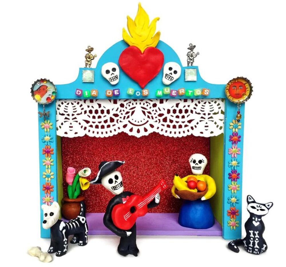 A turquoise folk-art altar box reading Dia de los Muertos with skeleton musicians