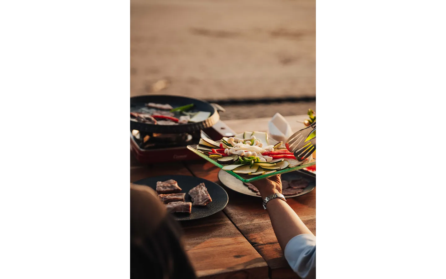 Hands reaching for a shared plate of appetizers at an outdoor table