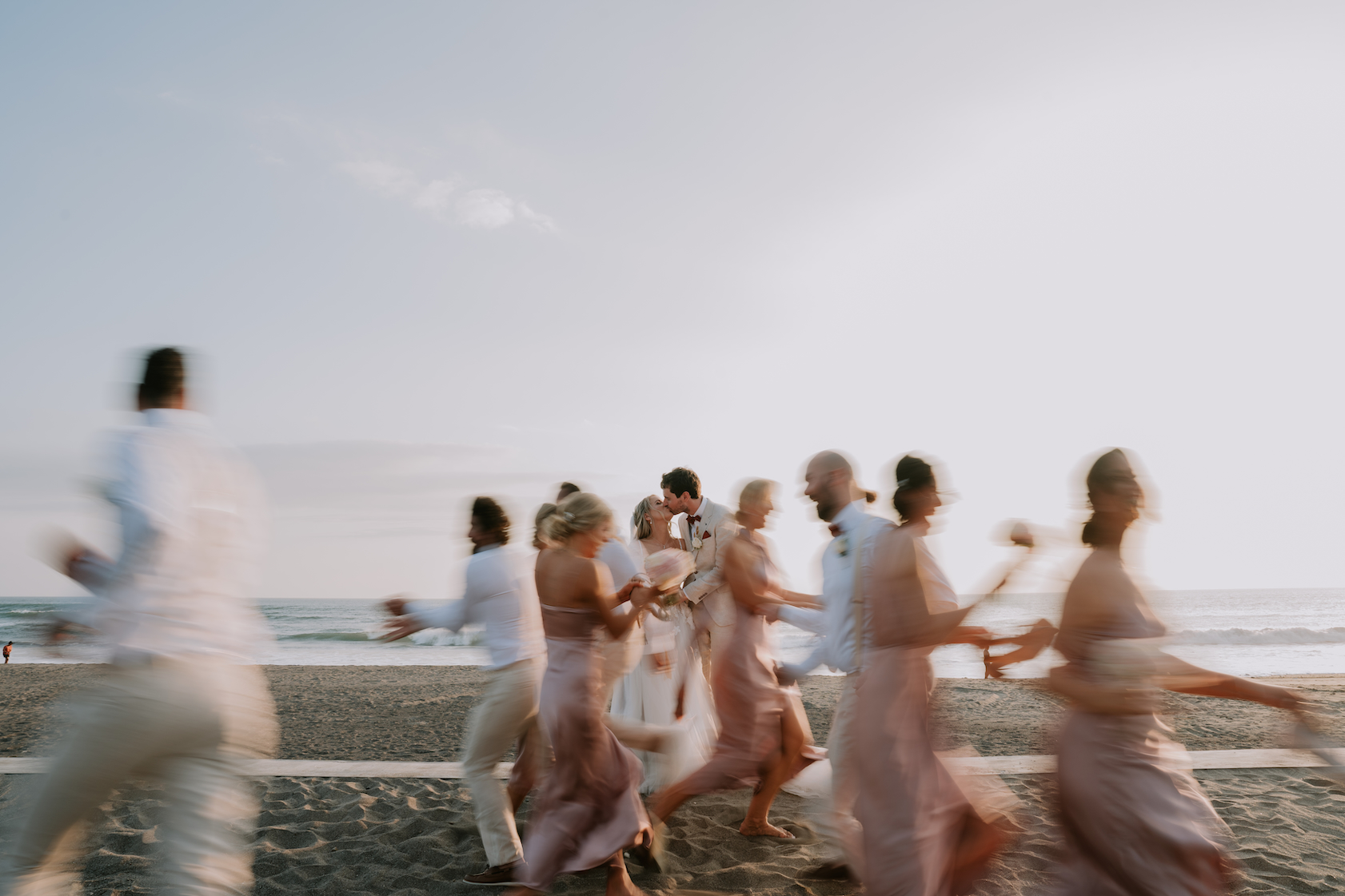 Bridal party running along the beach