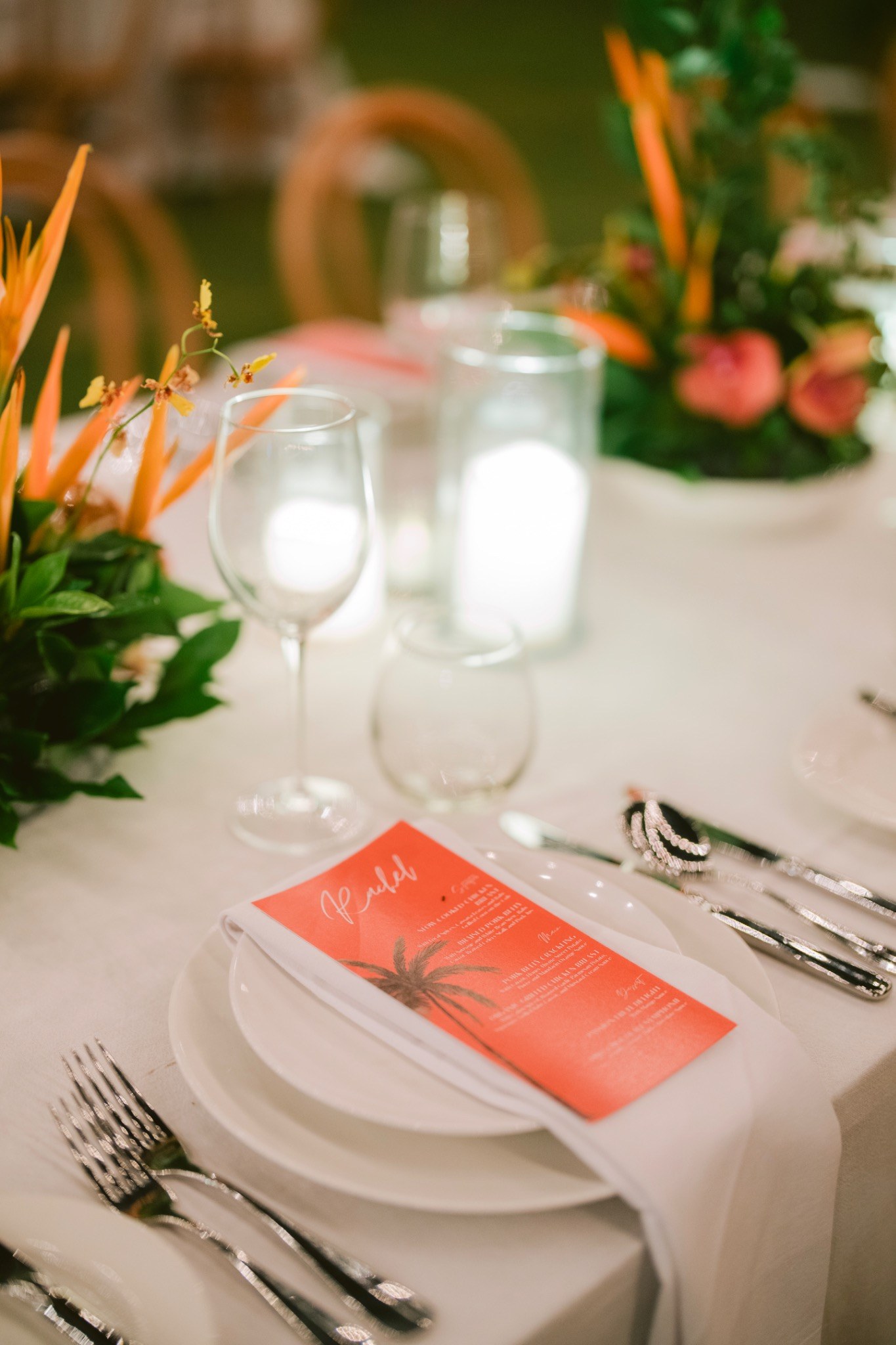 Elegant table setting with a tropical floral centerpiece, wine glasses and a menu card