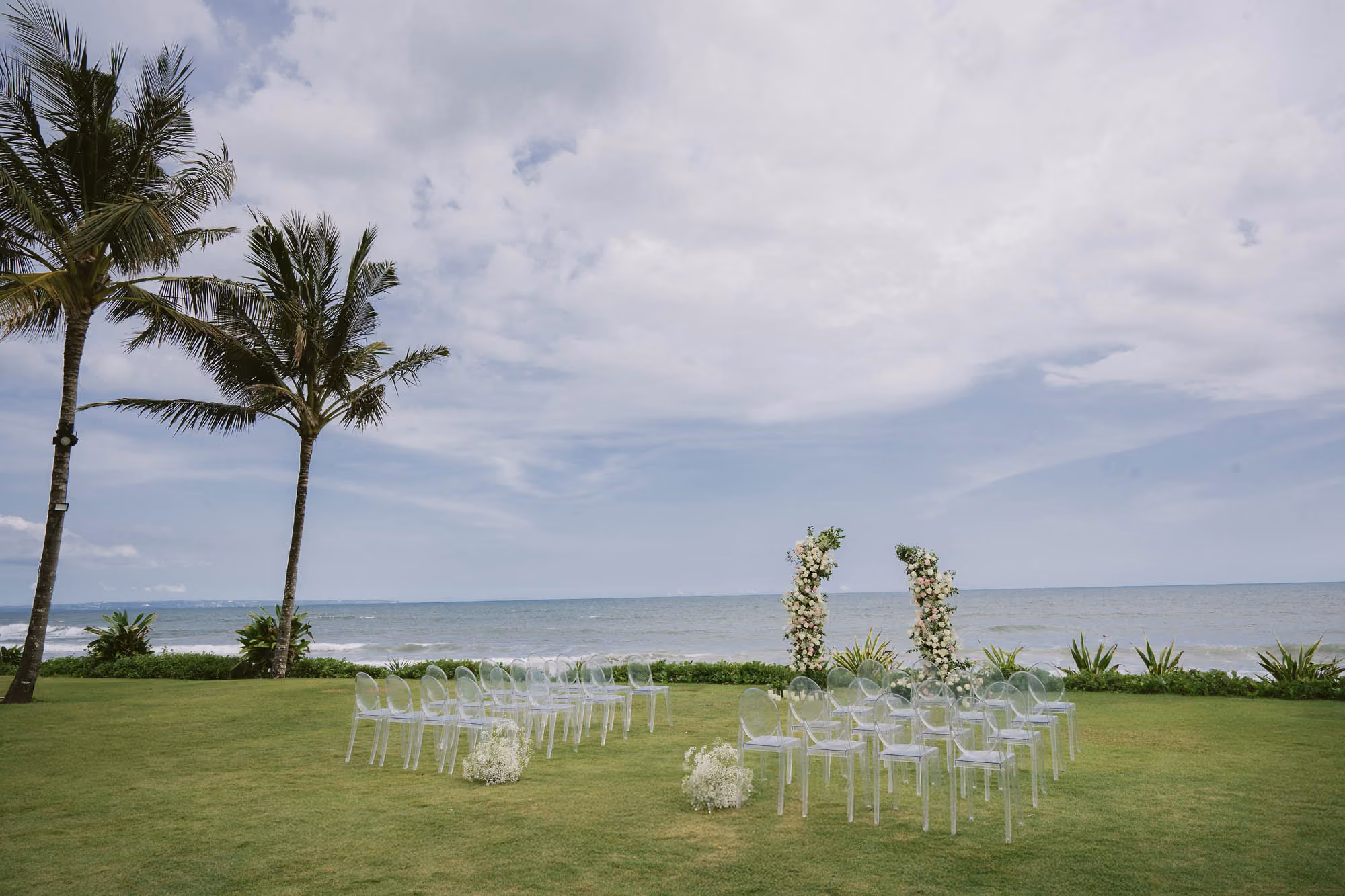 Wedding ceremony arch and empty chairs set up on the lawn overlooking the ocean
