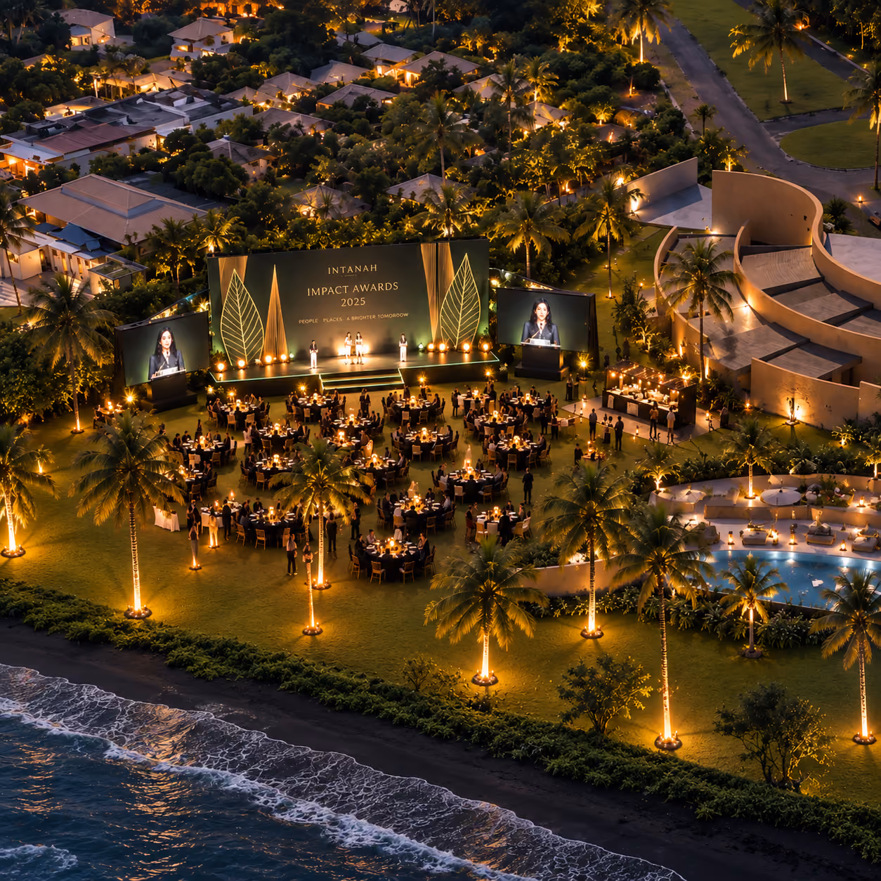 Aerial view of an oceanfront gala dinner with illuminated stage screens among palm trees