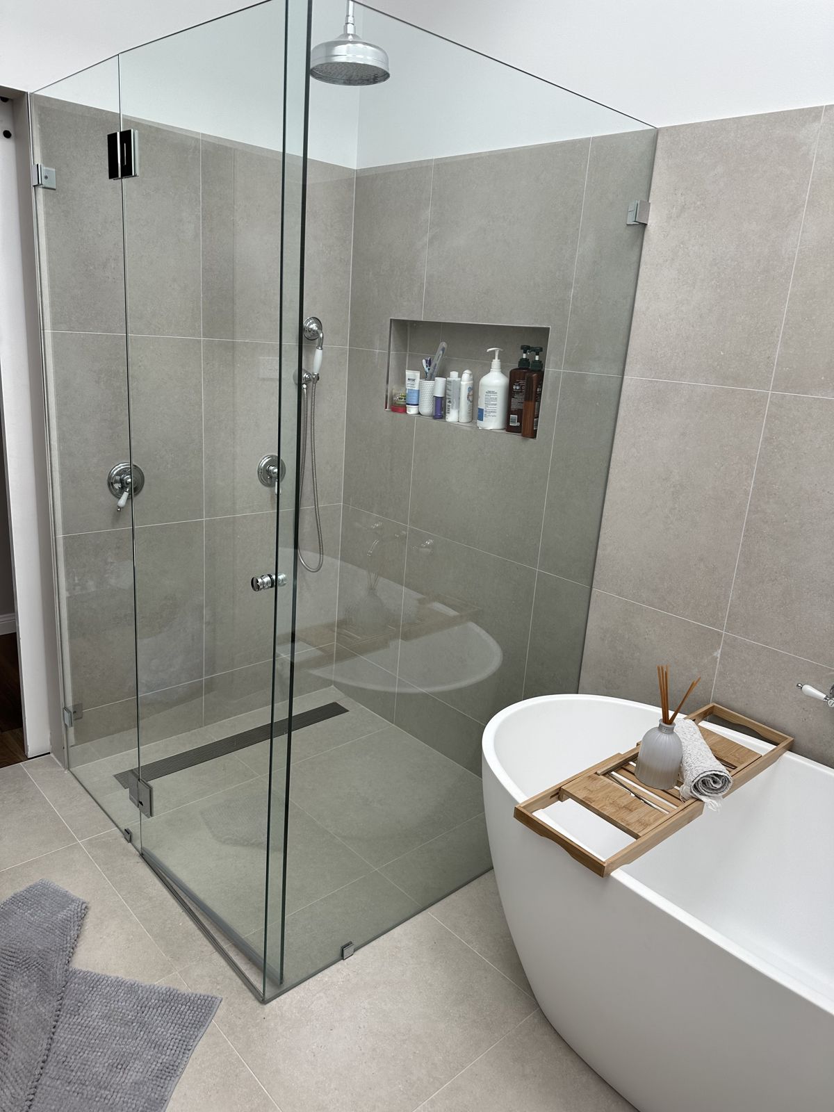 Frameless shower screen and freestanding bath after a deep clean in a Hawkesbury home
