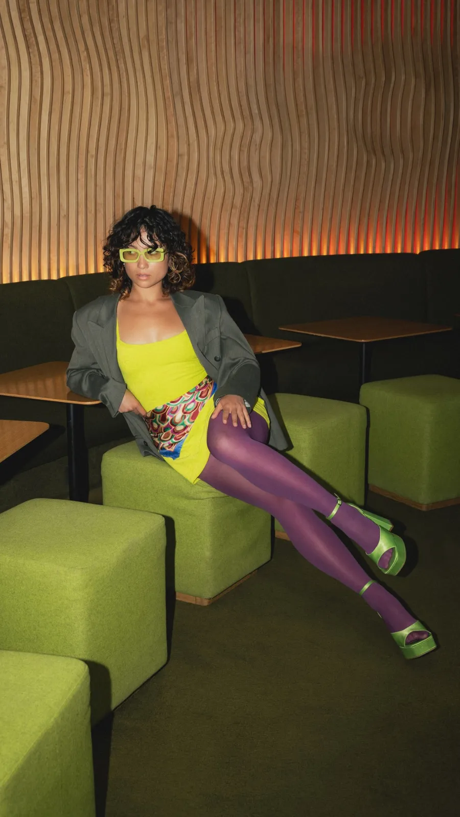 Femme en robe jaune assise sur les poufs verts, bar lounge design à Paris 1er