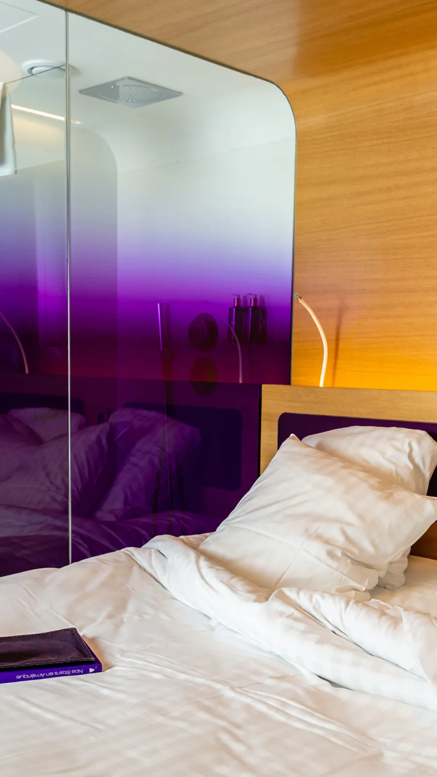 Purple glass wall and white bed, concept of the ORA-ÏTO design hotel, Paris 1st arrondissement