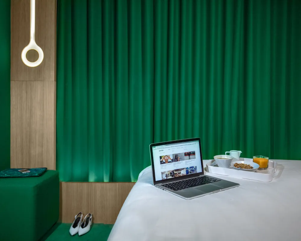 Chambre Cocoon verte, ordinateur et plateau sur le lit, hôtel capsule Paris 1er