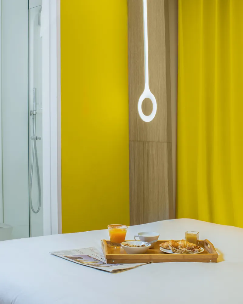 Plateau petit-déjeuner sur le lit, chambre Cocoon jaune, hôtel capsule Paris 1er