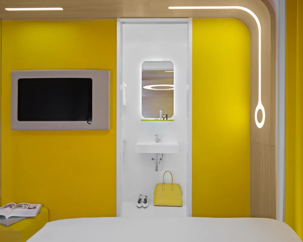 Chambre Cocoon jaune avec télévision murale, hôtel capsule à Paris 1er