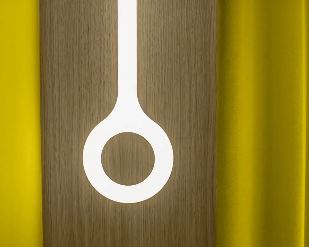 Luminaire en anneau signé ORA-ÏTO et rideaux jaunes, hôtel capsule à Paris 1er