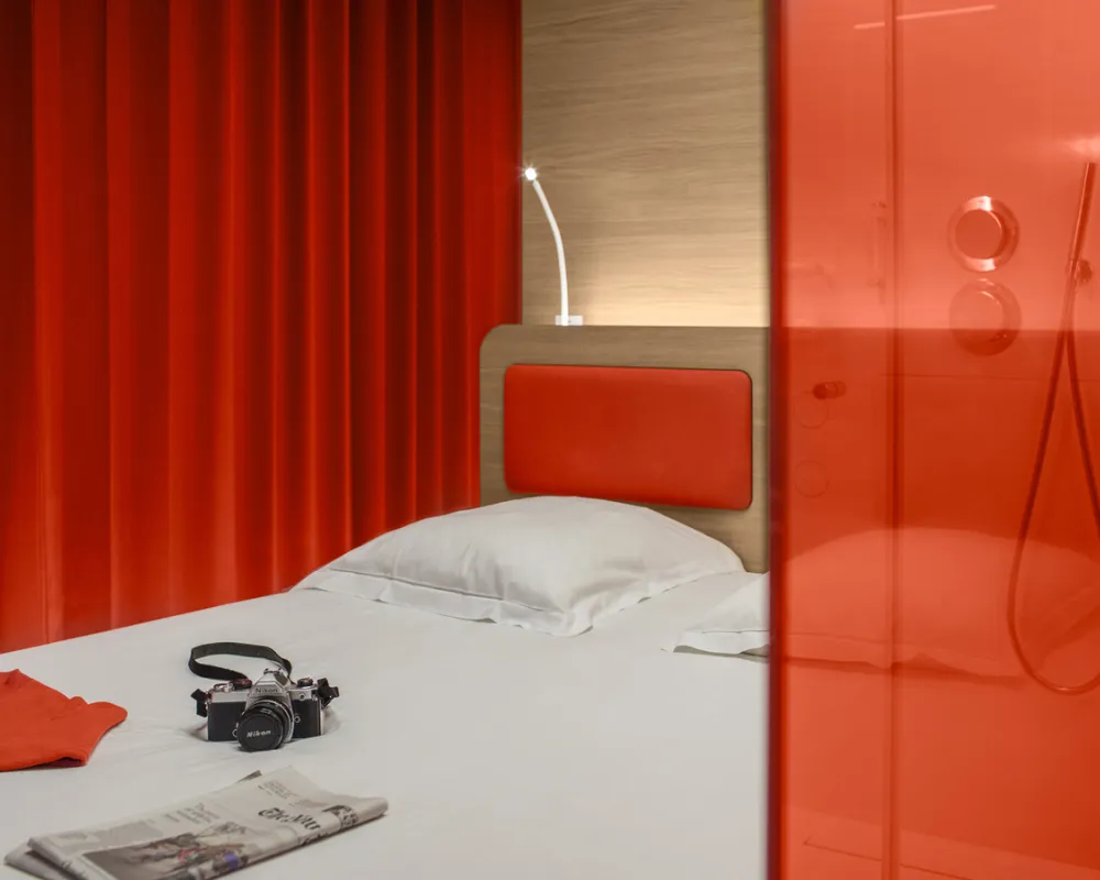 Chambre Odyssey rouge, rideaux vermillon et douche vitrée, hôtel capsule Paris 1er