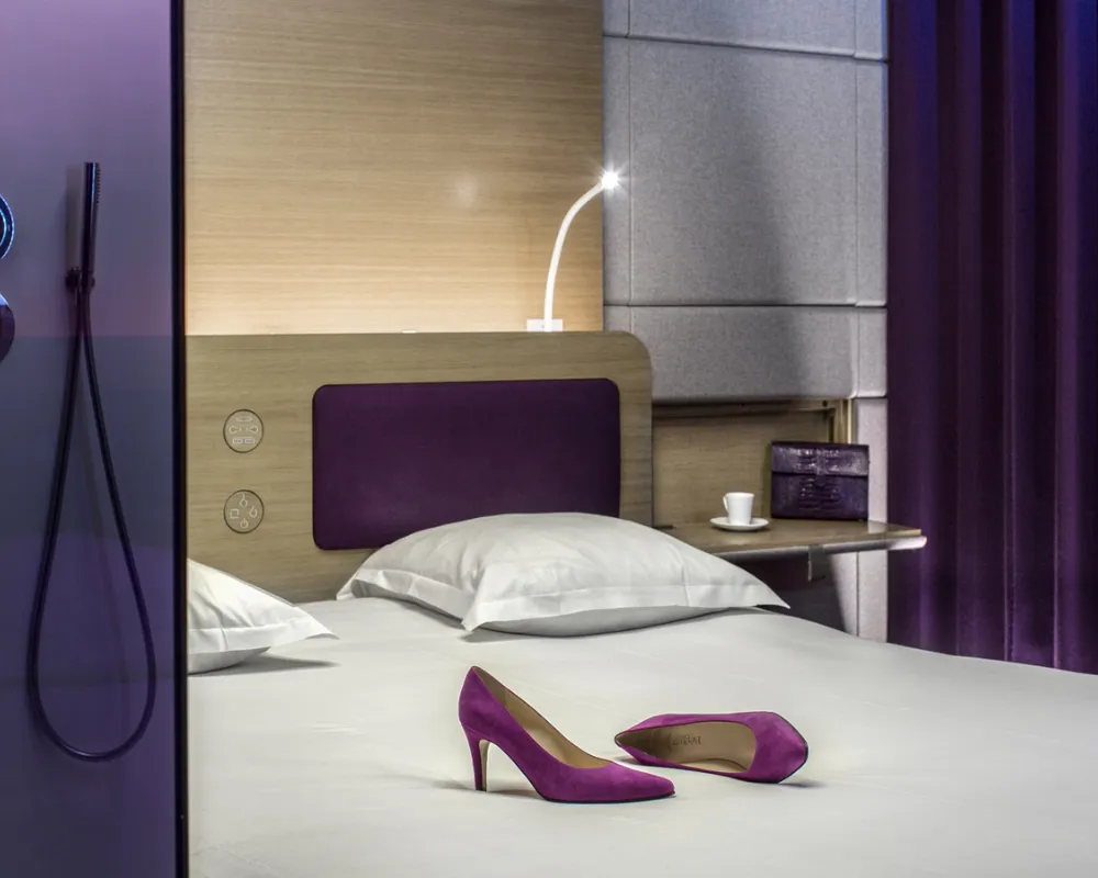 Chambre Odyssey violette, escarpins sur le lit, hôtel capsule à Paris 1er